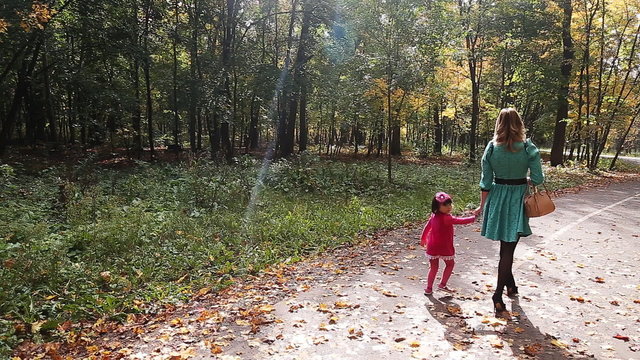 Mother and daughter walking in the park autumn