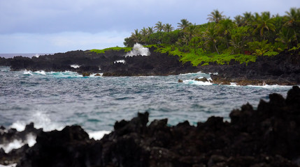 Fototapeta na wymiar Waves Break Against Volcanic Rocks in Maui, Hawaii
