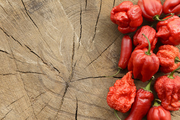 Various red hot peppers on a wooden background arranged on the right with space for content.