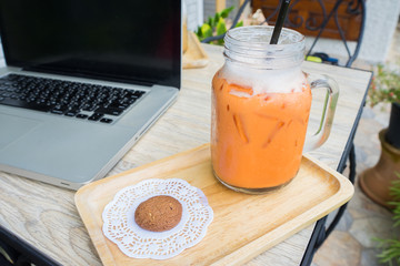 Iced milk tea with cookie and Laptop on the table 