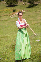 Frau im Dirndl im  mittleren Alter mit Wiesenblume im Mund und r