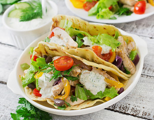 Mexican tacos with chicken, bell peppers, black beans and fresh vegetables and tartar sauce