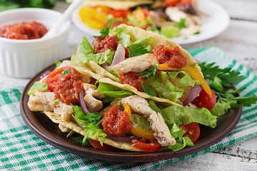 Mexican tacos with chicken, bell peppers, black beans and fresh vegetables and tomatoes sauce