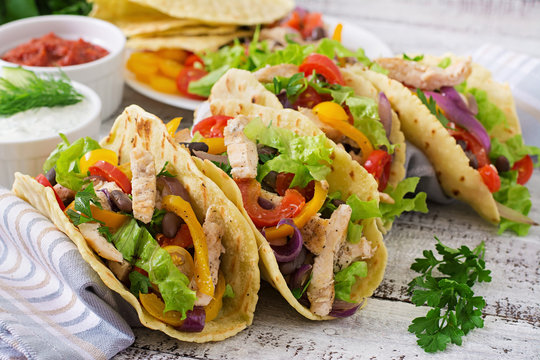 Mexican tacos with chicken, bell peppers, black beans and fresh vegetables.