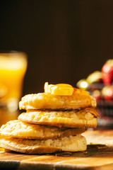 Toasted crumpets with honey drizzled over them and strawberries in the background.