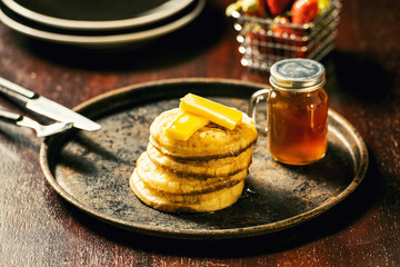 Toasted crumpets with honey drizzled over them and strawberries in the background.