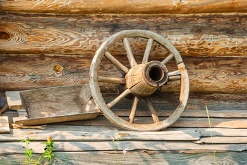 Obraz premium Old wooden wagon wheel in the background log wall