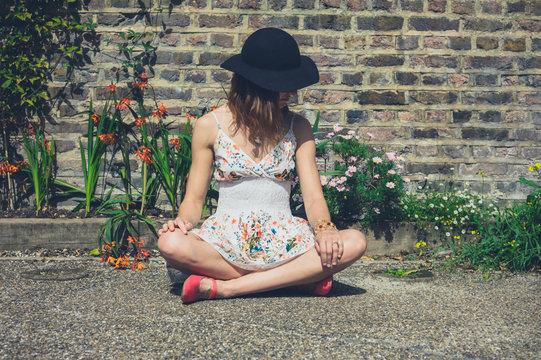 Young woman sitting by flowers outside