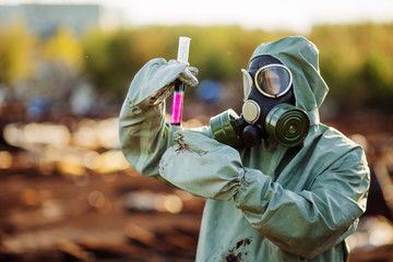 Man with gas mask and green military clothes explores barrels af