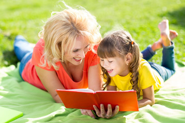 Happy mother with daughter in park reading book