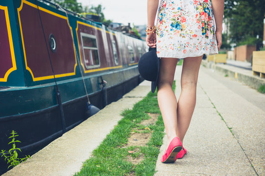 Young woman walking past houseboat on the canal