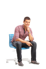 Vertical shot of a casual guy sitting on a chair