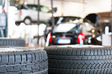 Reifenwechsel im Fachhandel - neue autoreifen in einer Werkstatt, im hintergrund Autos auf der...