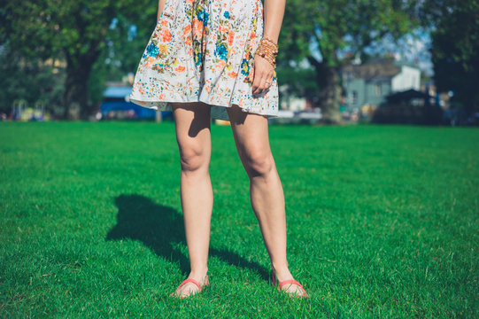 Woman in dress standing on grass in park