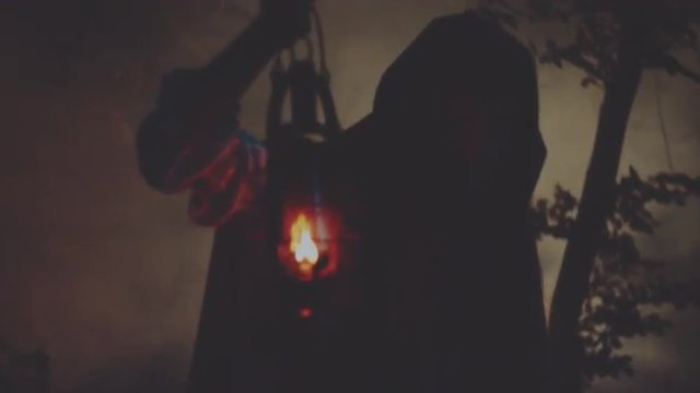 Young woman in a raincoat with a hood walking in night wood