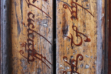 Detalle de una puerta de madera con inscripciones élficas, Girona - obrazy, fototapety, plakaty