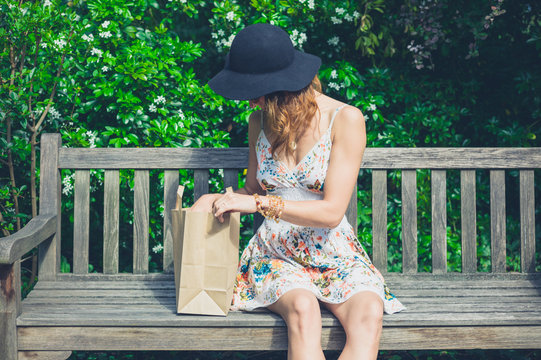 Young woman sitting on bench with paper bag