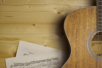 Guitar and Sheet music on wood.