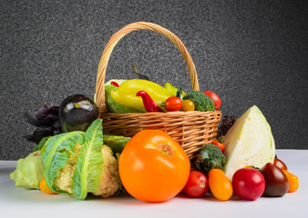 Still life of autumn vegetables in a basket on a gray background