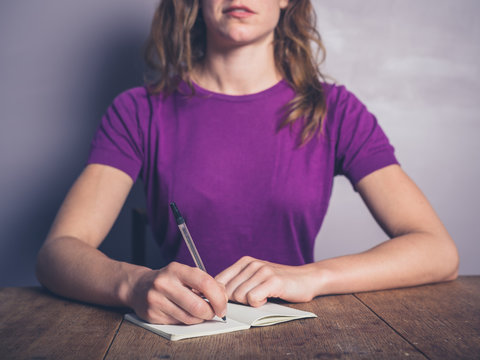 Thoughtful young woman writing in notepad