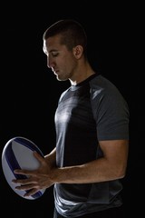 Calm rugby player thinking while holding ball