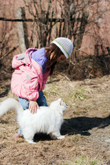 Cute little girl stroking white cat