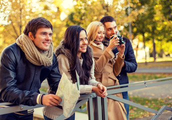 group of friends with map and camera outdoors