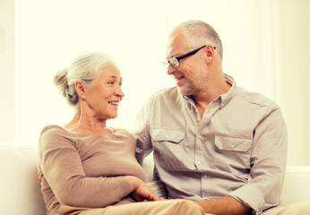 happy senior couple hugging on sofa at home