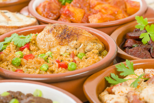 Arroz Con Pollo - Chicken and rice cooked with sofrito and beer. Surrounded by other tapas dishes.