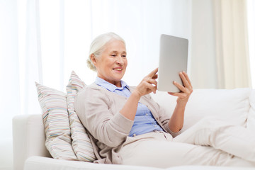 happy senior woman with tablet pc at home