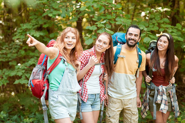 group of smiling friends with backpacks hiking