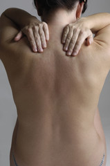 Nude woman with back pain on a gray background