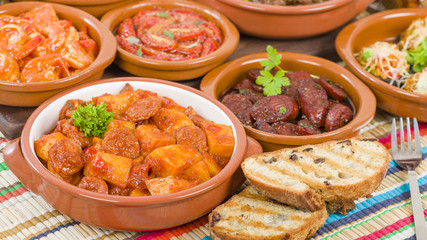 Tapas - Selection of latin dishes. Chorizo al vino, Higados de pollo, Chicken and chorizo, Tomates al ajillo, Arroz con pollo, Camarones enchilhados, Patatas a ala riojana and Stuffed mushrooms.

