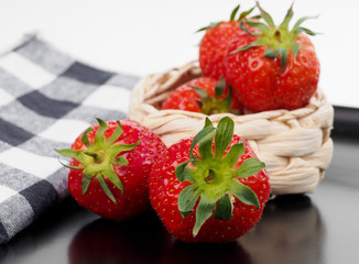 Red strawberries arranged on a black plate