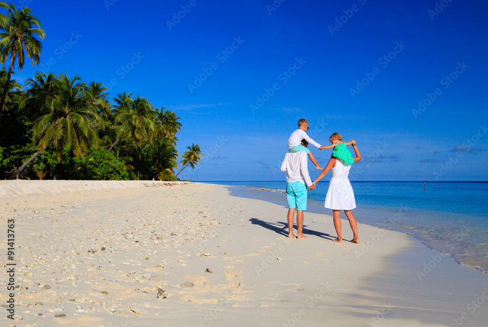 Wall mural Young family with two kids walking at beach