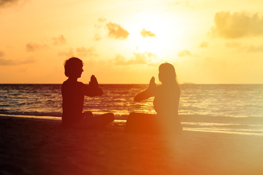 silhouette of couple doing yoga at sunset