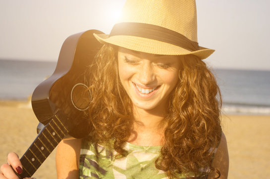 girl smile at the beach while she is taking her guitar - people, music and lifestyle concept