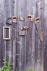 Antique handicraft tools and horseshoe hanging on old  wall
