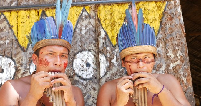 Native Brazilians playing wooden flute at an indigenous tribe in the Amazon