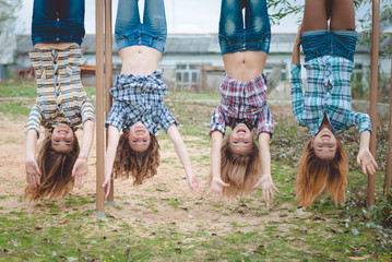 Four young funny teenage girls hanging upside down having fun 