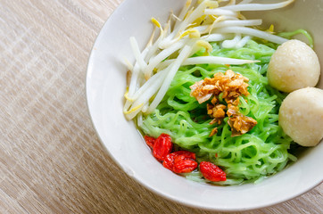 Close up Thai Noodle with meat ball and crispy pork skin on wood