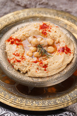 Hummus, chickpea dip, with rosemary, smoked paprika and olive oil in a metal bowl .selective focus