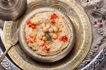 Hummus, chickpea dip, with rosemary, smoked paprika and olive oil in a metal bowl .selective focus