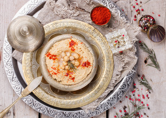 Hummus, chickpea dip, with rosemary, smoked paprika and olive oil in a metal bowl .selective focus