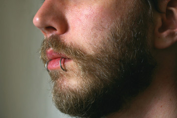 Close up of a mans face with a piercing