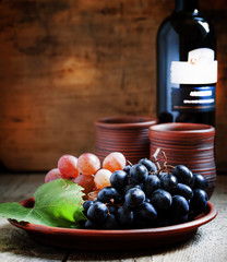 Blue and pink grapes on a clay plate and wine in rustic style, s