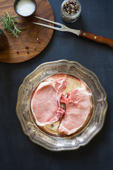 Raw pork rib chops on the metal plate with spices and herbs