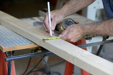 Worker Measuring Wood to Cut on Table Saw