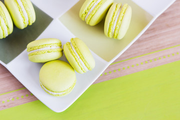 Green macaroons on a square plate. Top view