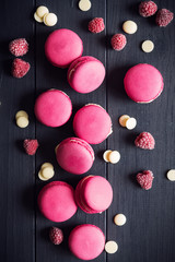Raspberry macaroons on black wooden background